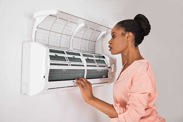 Woman checking faulty air conditioner