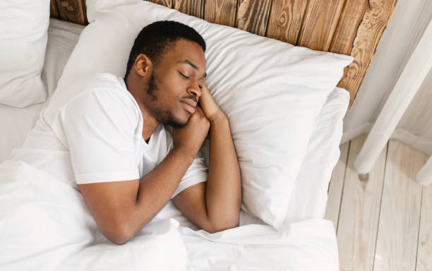 African American Man Sleeping Peacefully Resting With Eyes Closed Lying In Comfortable Bed In Bedroom At Home.