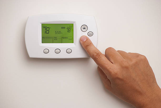 Programmable Thermostat with a male hand, set to 78 degrees Fahrenheit. Saved with clipping path for thermostat and hand combined.