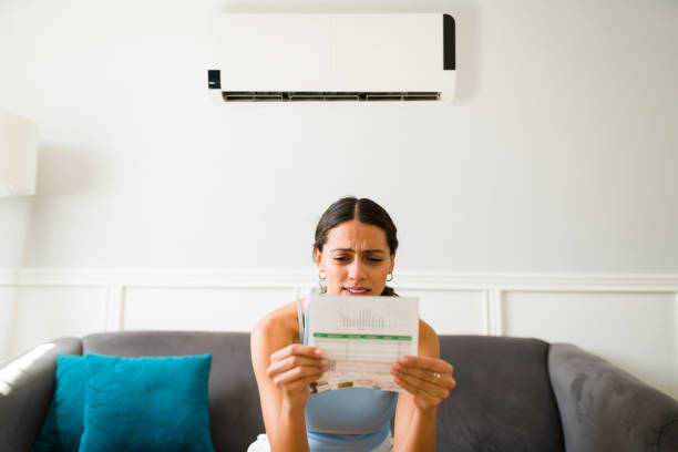 Worried young woman looking stressed while receiving the electricity bill seeing how much does it cost to run an air conditioner at home