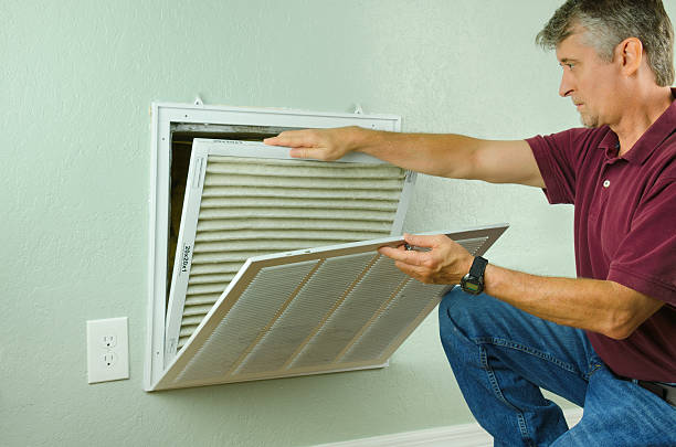 Professional repair service man or diy home owner removing a dirty air filter on a house air conditioner so he can replace it with a new clean one. Surrey Air Heating and Cooling 7/84-90 Lakewood Blvd, Braeside VIC 3195, Australia. 61395517460