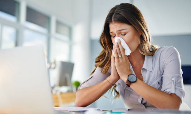 A businesswoman working in her office while suffering from allergies to pollen and dust