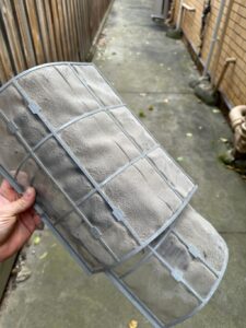 Surrey air technician working on a dirty air conditioner filter