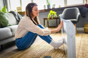 woman warming up near oil heater focusing on How does an oil heater work?